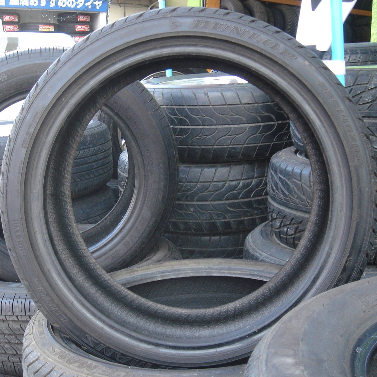 Passenger car tires stacked on their sides, tread and sidewalls visible